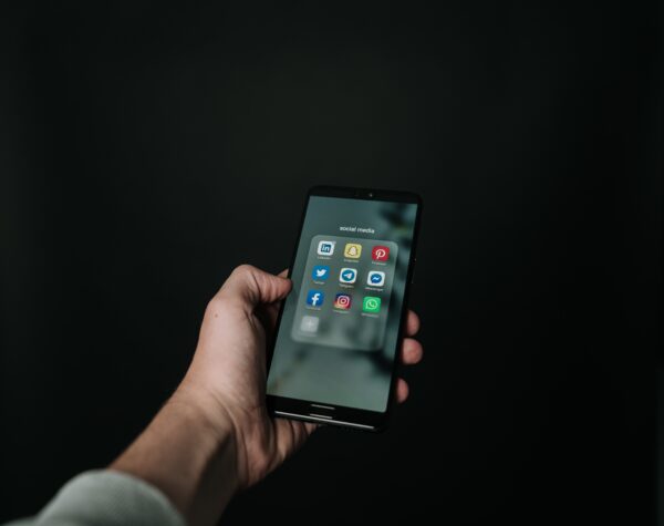 A smartphone on the home screen displays social media apps and illustrates using social media for business.