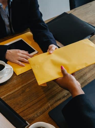 Operations consultant handing over an envelope.